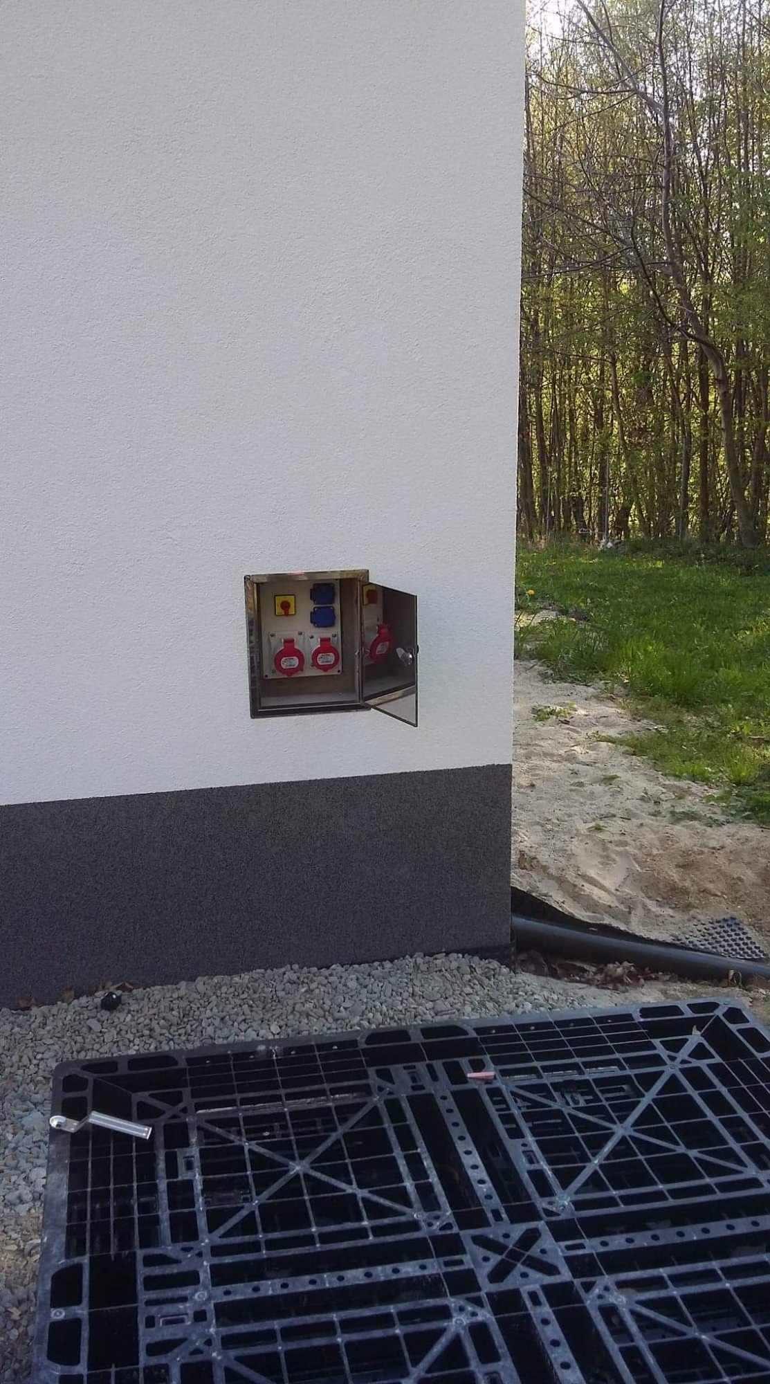 Skrzynka siłowa zabudowana w elewacji z drzwiami kajnerowymi.