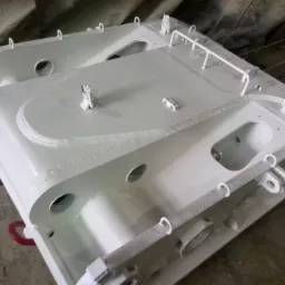 Pomalowany na biało element konstrukcji stalowej z licznymi otworami i uchwytami, widoczne ślady spawania i numer seryjny.