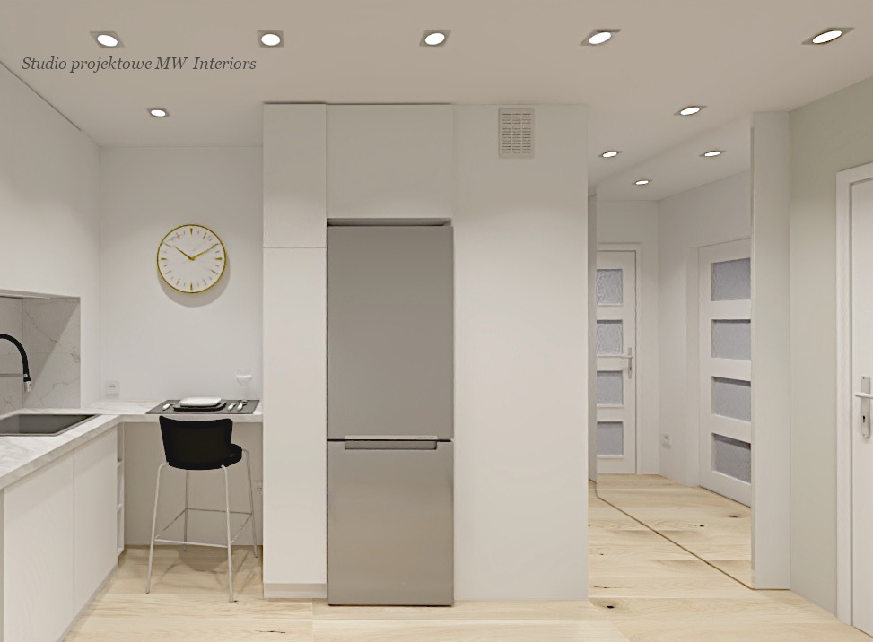 Minimalistyczna kuchnia z białymi szafkami, szarą lodówką i drewnianą podłogą, złoty zegar na ścianie, nowoczesne oświetlenie punktowe.