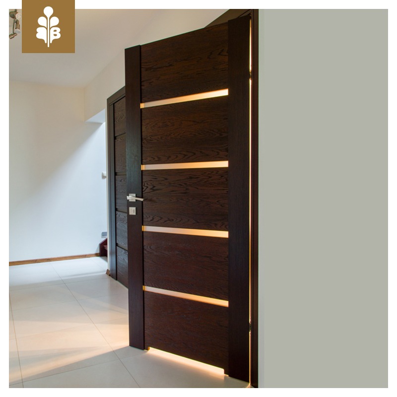Ciemne, fornirowane skrzydło drzwiowe z poziomymi, podświetlanymi wstawkami, częściowo otwarte, widok na korytarz z drugimi drzwiami w tle.