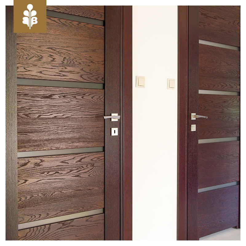 Dwa skrzydła drzwiowe z ciemnego drewna z poziomymi przeszkleniami, widoczne klamki i zamki, jasne włączniki na ścianie.