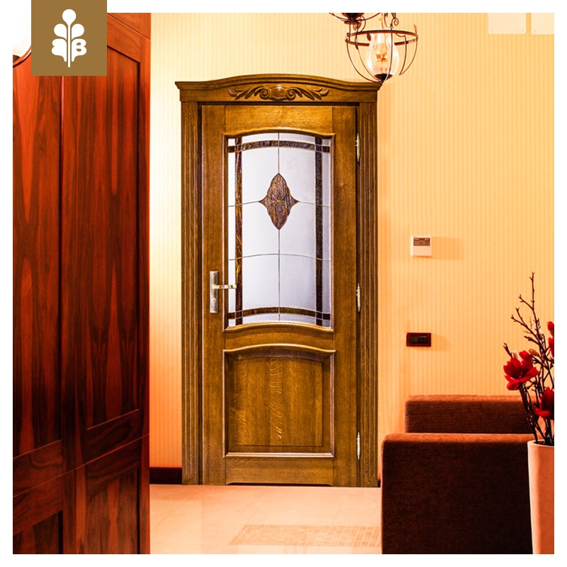 Eleganckie drzwi wewnętrzne z drewnianą ramą, zdobionym ornamentem i szybą z dekoracyjnym wzorem, oświetlone ciepłym światłem żarówki w metalowej klatce.