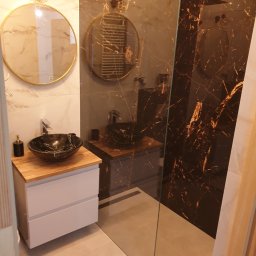 Alwent - Nowoczesna łazienka w Nadarzynie z umywalką nablatową z czarnego marmuru, okrągłym lustrem z podświetleniem LED i kabiną prysznicową typu walk-in z ciemnymi płytkami imitującymi marmur.