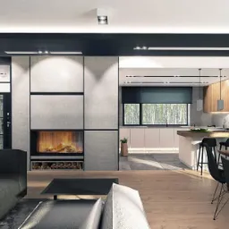 Nowoczesne wnętrze domu z otwartą przestrzenią: salon z kominkiem i kuchnia z wyspą, drewniana podłoga, czarne detale, duże okno z widokiem na zieleń.