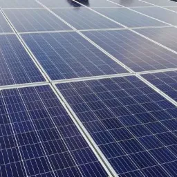 Panele słoneczne na dachu z czarnej dachówki, widoczna drabina oparta o dach.