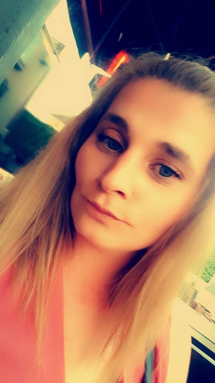 Portret kobiety z blond włosami i niebieskimi oczami, ujęcie z dołu, lekko rozmyte.