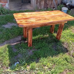 GUT-DREW GRZEGORZ GUTOWSKI - Drewniany stolik z polerowanym blatem, stojący na trawie przed budynkiem gospodarczym.