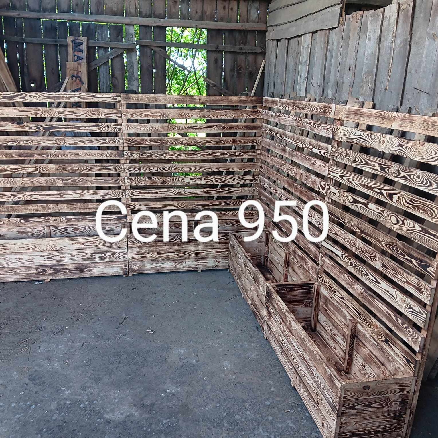Drewniana konstrukcja z tarcicy budowlanej wewnątrz drewnianego budynku, z widoczną ceną 950, prawdopodobnie ogrodzenie lub ścianka działowa.
