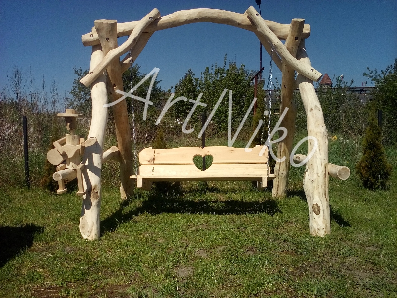 Drewniana huśtawka ogrodowa z rzeźbionym siedziskiem w kształcie serca i dekoracyjną figurką grającego na gitarze, wykonana z naturalnych pni drzew.