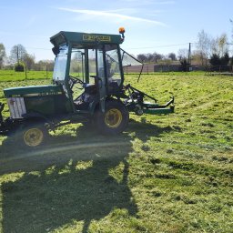 Kop Wiktor Gniado - Zielony traktor John Deere 855 z żółtymi felgami kosi trawę na polu w słoneczny dzień, widoczny efekt koszenia i logo firmy KOP na kabinie.