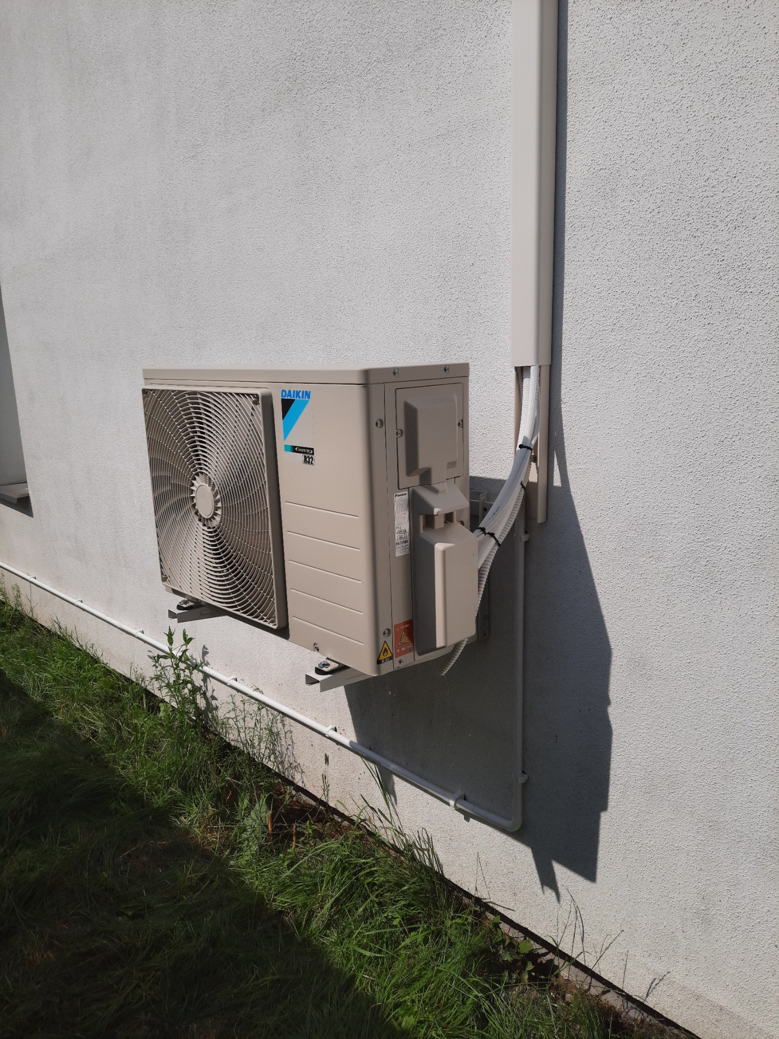 Zewnętrzna jednostka klimatyzacji Daikin zamontowana na elewacji budynku w Sowlany, widoczne przewody w białej listwie maskującej.