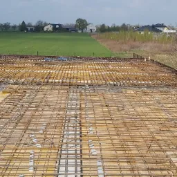 Zbrojenie stropu na deskowaniu z widokiem na okoliczne domy i pola uprawne.