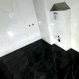 Nowoczesna łazienka w trakcie wykańczania: czarne płytki podłogowe imitujące marmur z białymi żyłami kontrastują z białymi ścianami wyłożonymi płytkami z szarym wzorem żyłkowania, widoczne...