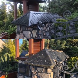 Chrzan-Dach - Metalowe pokrycie daszku nad kamiennym słupkiem ogrodzenia z ozdobnym metalowym elementem, widoczne ślady korozji i zabrudzeń.