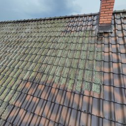 ZACZYSZCZONE PIOTR STĘPNIAK - Częściowo oczyszczony dach z ceglastą dachówką, widoczny komin z cegły i fragment pochmurnego nieba.