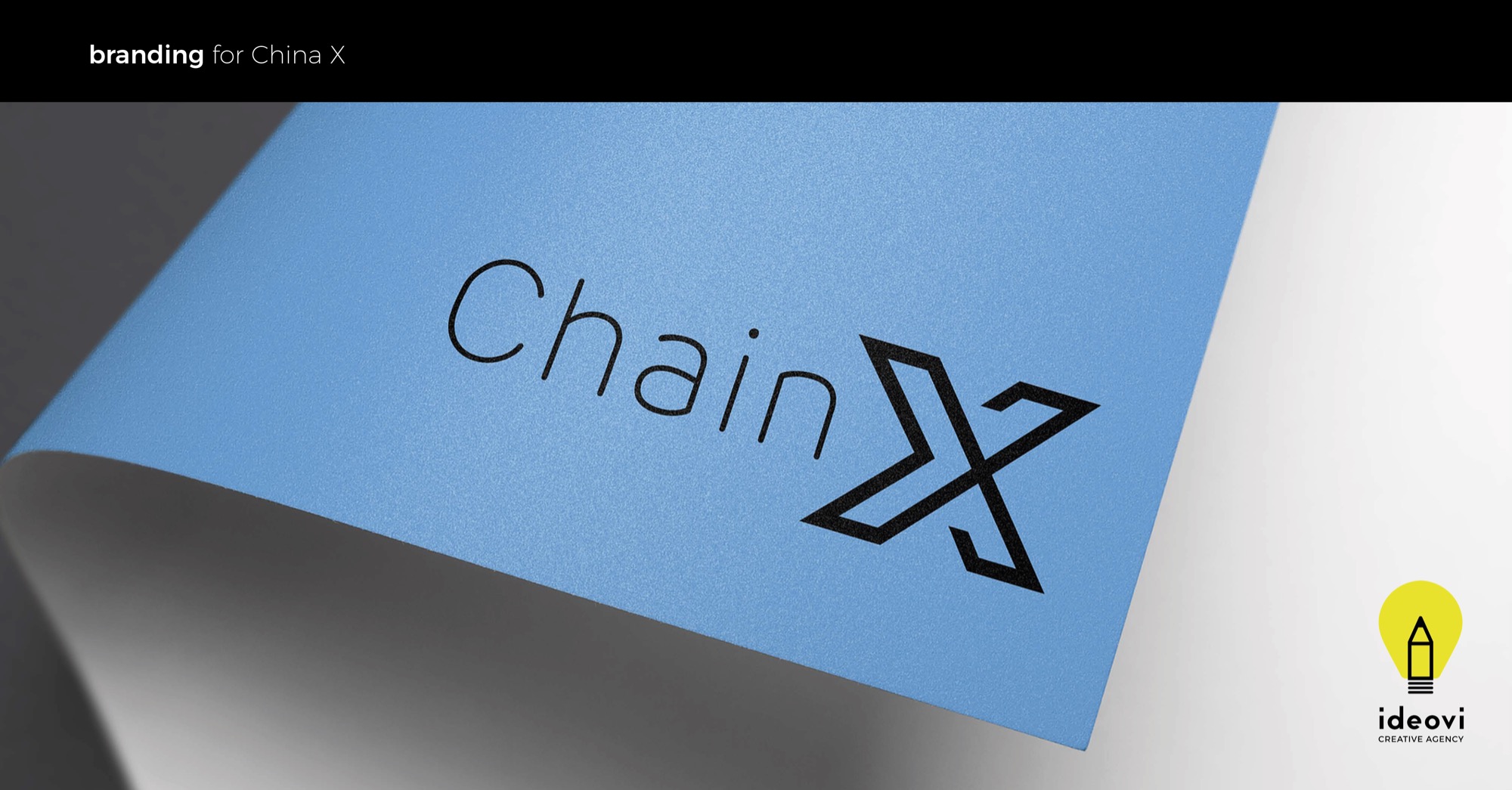 Błękitna kartka papieru z nadrukowanym czarnym logo 'ChainX' w minimalistycznym stylu, z logo agencji 'ideovi' w prawym dolnym rogu.