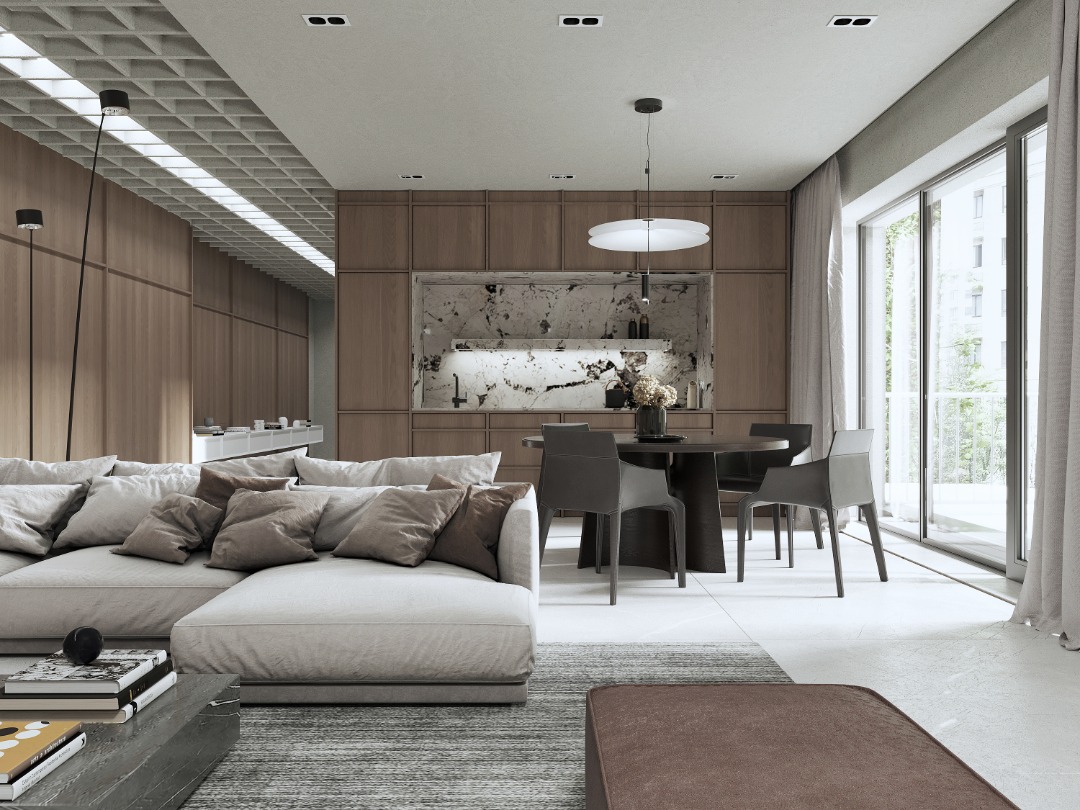 Nowoczesny salon z narożną sofą w odcieniach szarości, okrągłym stołem jadalnym i marmurowym blatem kuchennym w tle, doświetlony dużymi oknami.