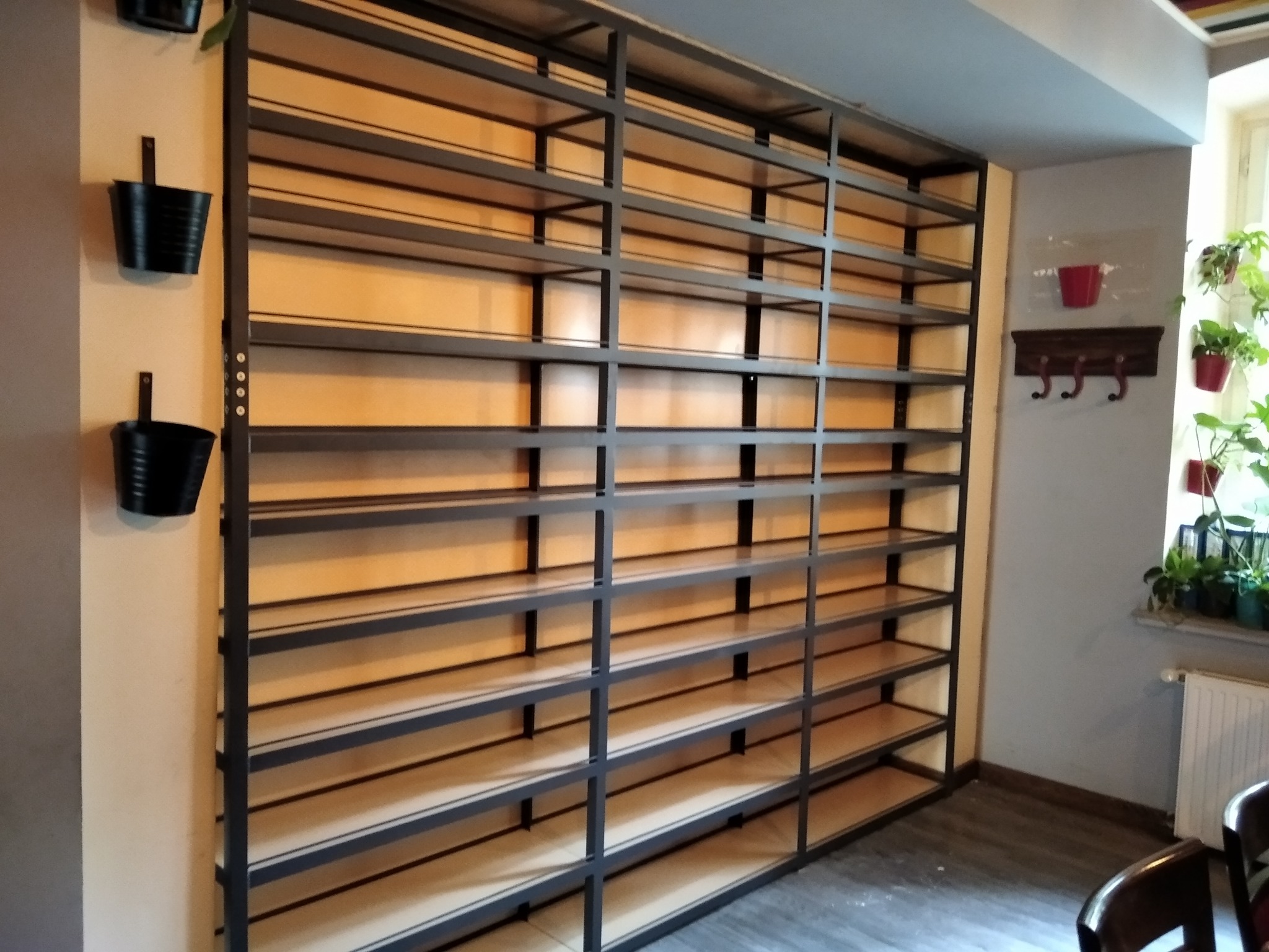 Metalowa konstrukcja regału z drewnianymi półkami, wykonana na wymiar w Poznaniu, z widocznymi detalami spawów i mocowań.