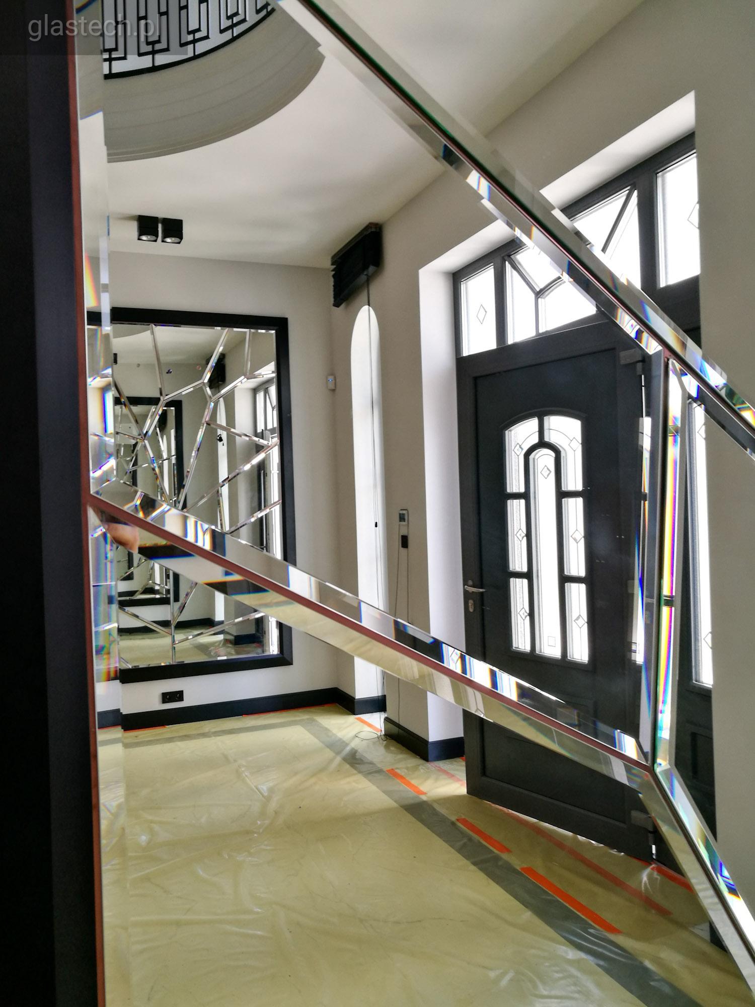 Nowoczesne szklane balustrady schodowe z efektem pryzmatu, widok z dołu na zabezpieczoną folią podłogę i lustro z geometrycznym podziałem w tle.