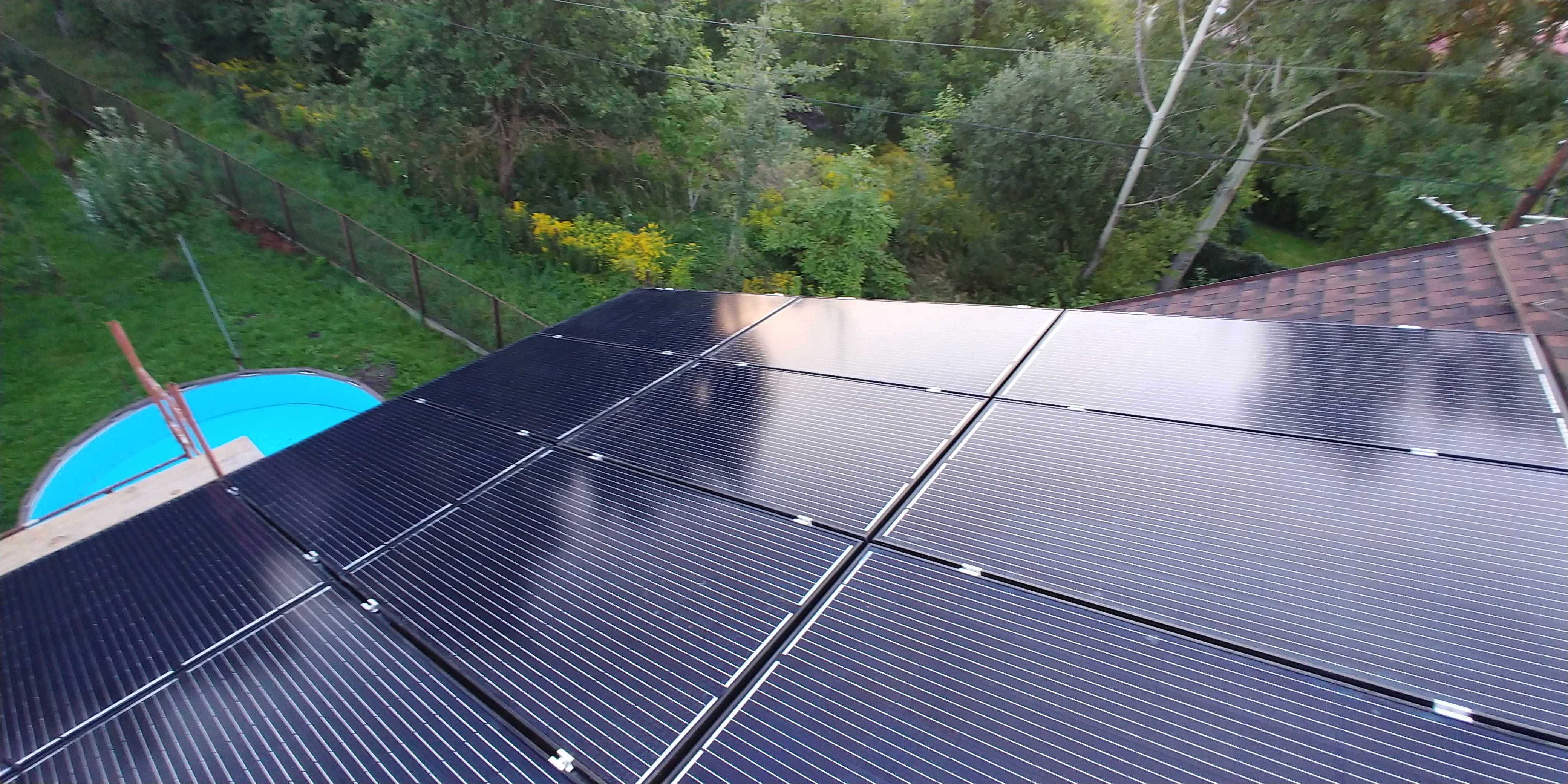 Panele słoneczne zamontowane na dachu w Sosnowcu, widok z góry na instalację z fragmentem ogrodu w tle.