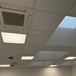 Klima Siedlce Tomasz Pawlik - Sufit kasetonowy z wbudowaną klimatyzacją kasetonową, oświetleniem LED i elementami wentylacji. Widok z dołu, oświetlenie mieszane.