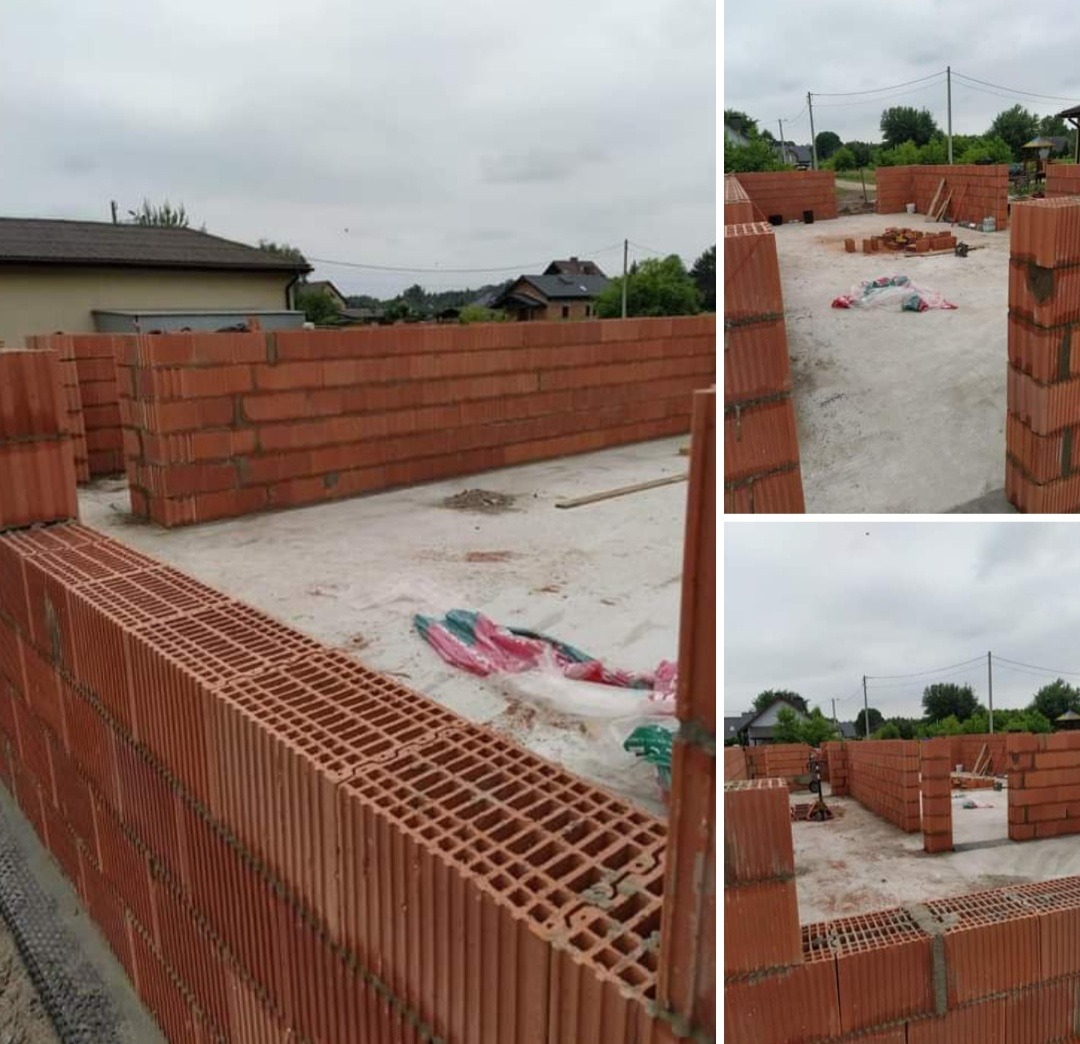 Wznoszenie ścian zewnętrznych z czerwonej cegły dziurawki na fundamencie, widoczne fragmenty izolacji i folii budowlanej, w tle zabudowa jednorodzinna i pochmurne niebo.