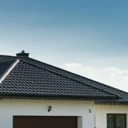 Nowoczesny dom jednorodzinny z ciemną, metalową dachówką, widok z dołu na dach, komin i fragment elewacji z numerem 7A.