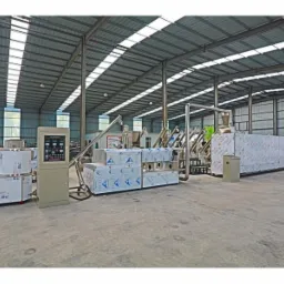 Widok hali produkcyjnej z zainstalowaną, dużą linią technologiczną, zabezpieczoną folią ochronną, z metalowymi rurami i szafą sterowniczą z wyświetlaczami.