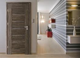 Drewniane drzwi wewnętrzne z poziomymi, ciemnymi pasami na tle nowoczesnego wnętrza z dekoracyjną ścianą w paski i oświetleniem punktowym.