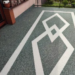 Szaro-zielona posadzka jastrychowa na balkonie z geometrycznym wzorem w jasnym odcieniu, widok z góry, balustrada w tle.