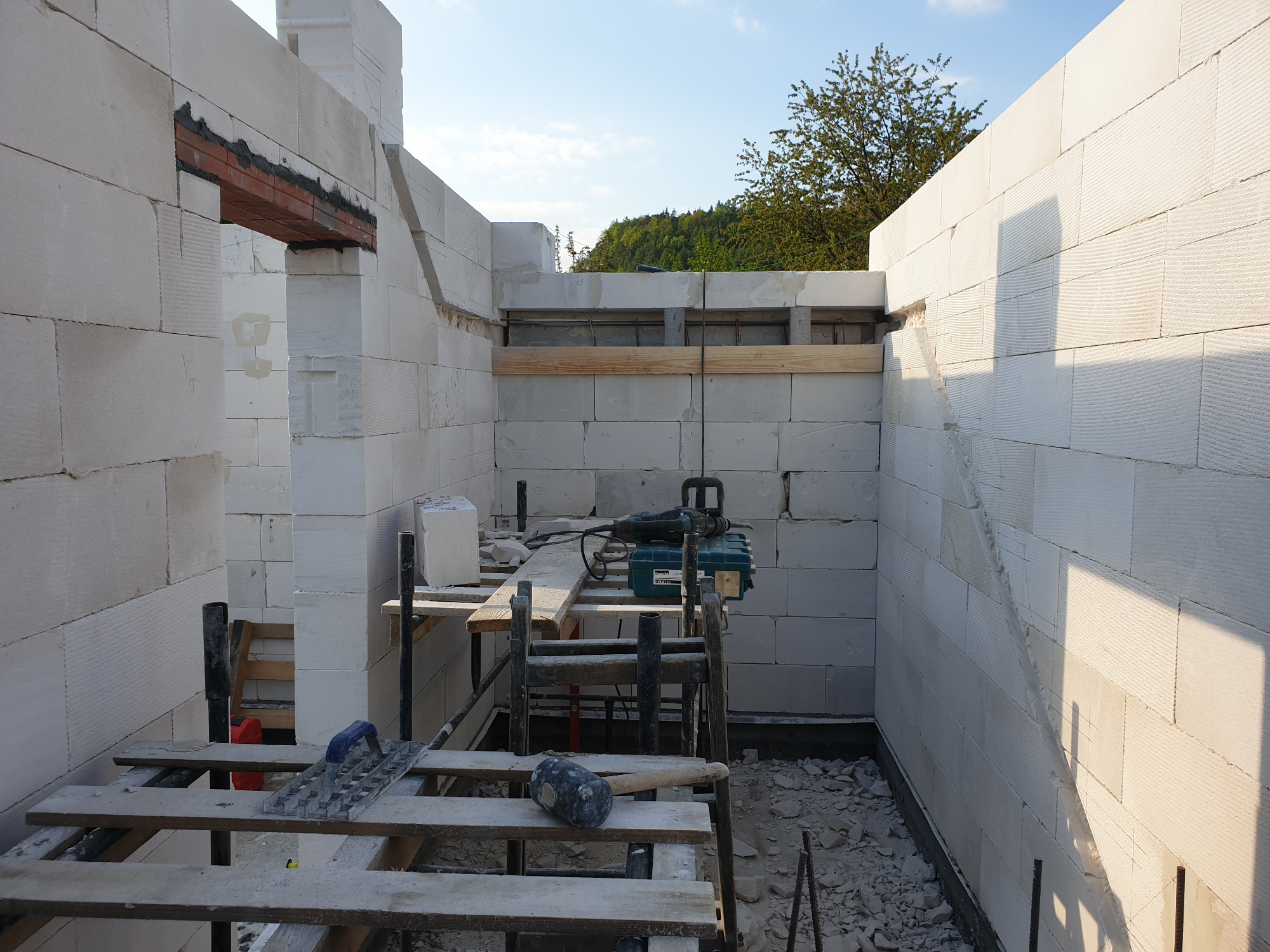 Wnętrze domu w trakcie budowy w Suchej Beskidzkiej, ściany wzniesione z białych bloczków, widoczne rusztowania i narzędzia budowlane.