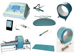 Zestaw urządzeń do magnetoterapii: aparat z ekranem dotykowym, aplikatory o różnych kształtach (pierścieniowy, płaski, punktowy), oraz łóżko z aplikatorem pierścieniowym, na którym leży pacjentka.