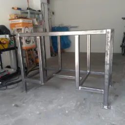 Metalowa konstrukcja stołu z profili kwadratowych, spawana, surowa, w garażu, widoczne spawy.