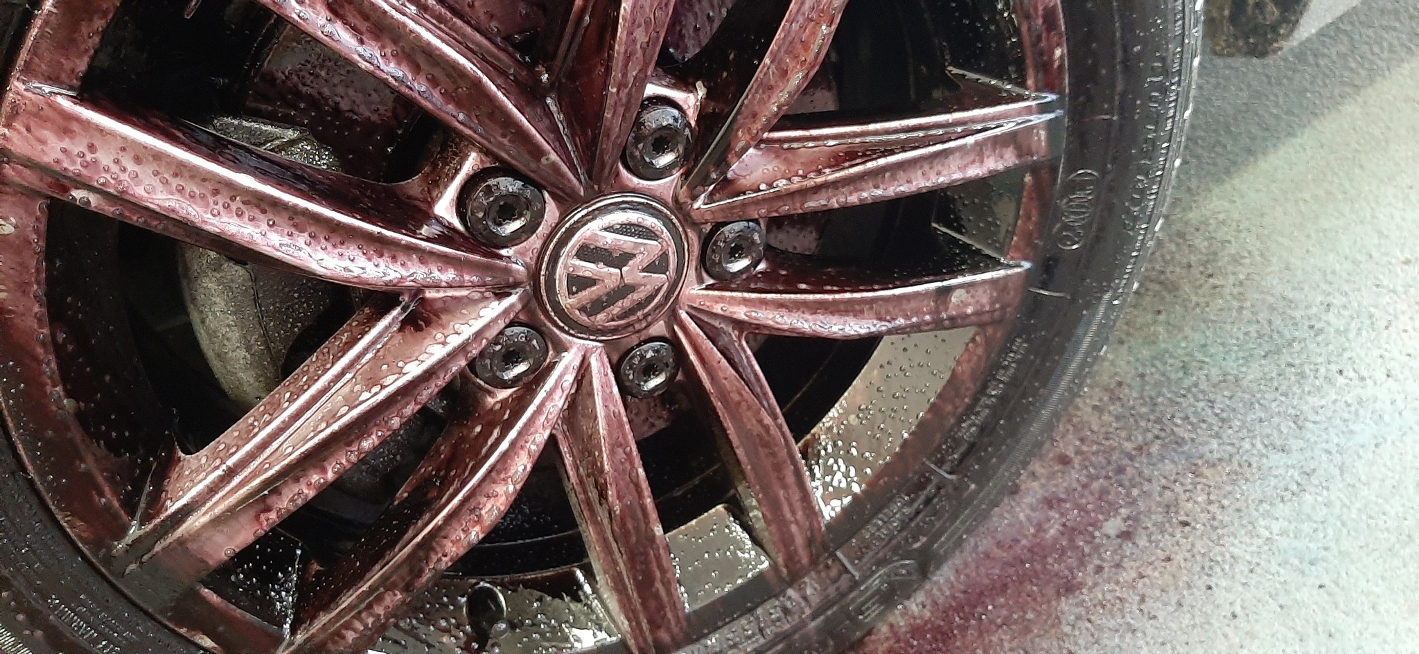 Aluminiowa felga Volkswagen po użyciu preparatu do czyszczenia felg, z widocznymi kroplami płynu i zaciekami.