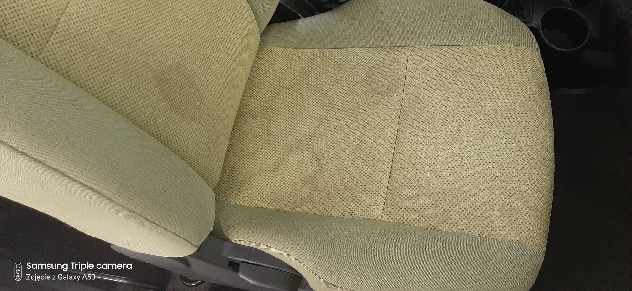 Beżowy fotel samochodowy z widocznymi plamami na tapicerce, ukazujący potrzebę czyszczenia.