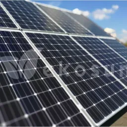 Panele słoneczne na dachu domu w słoneczny dzień, widoczne moduły fotowoltaiczne z bliska, błękitne niebo w tle.