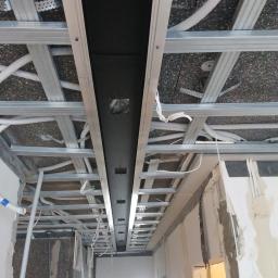 RED DIAMOND Remonty i wykończenia - Sufit podwieszany w trakcie montażu, widoczne profile stalowe, instalacja elektryczna w peszlach i czarna zabudowa oświetleniowa z otworami na oprawy.