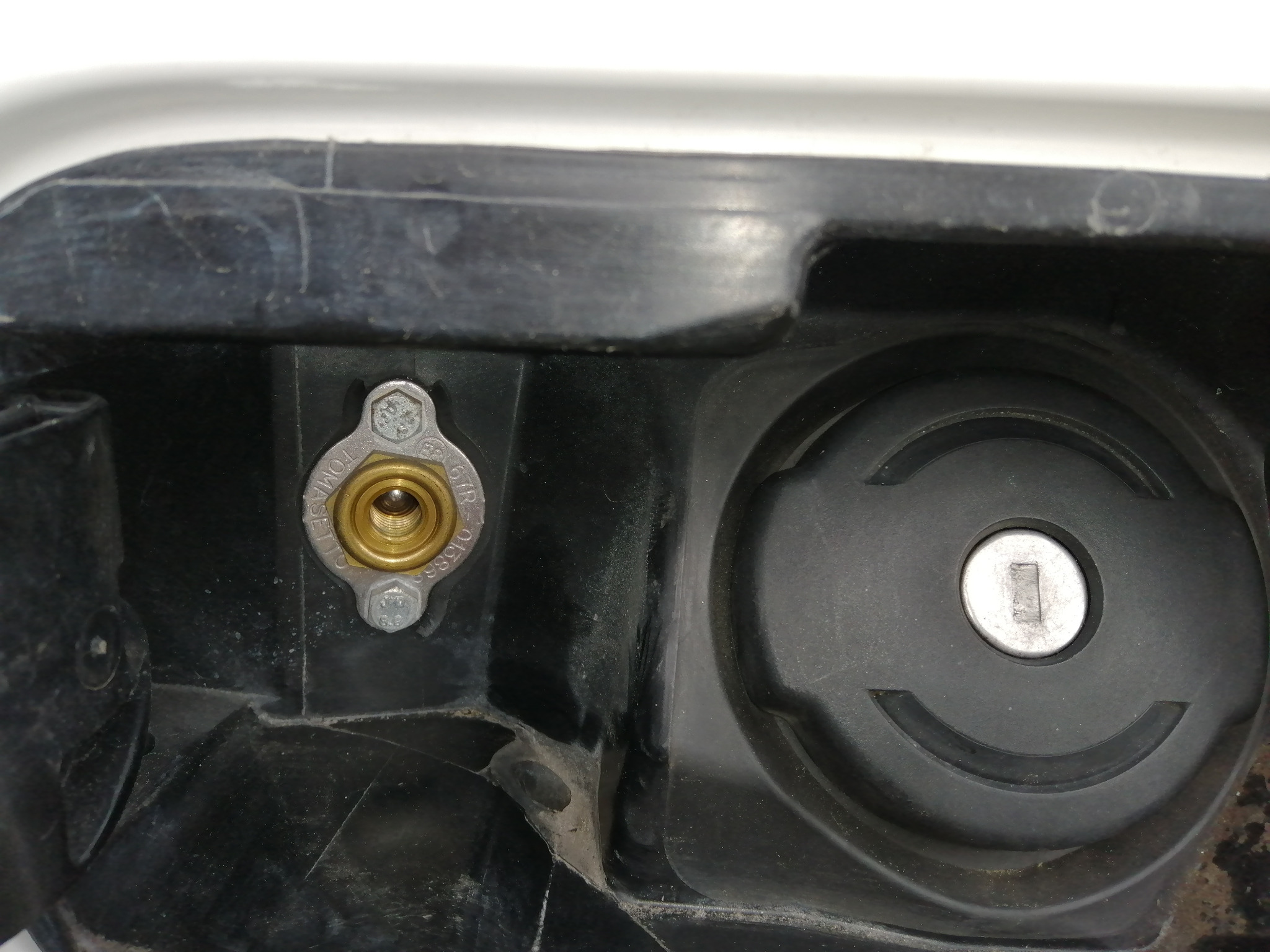 Zamknięty wlew gazu LPG z metalową obudową i złotym gwintem w czarnej plastikowej obudowie wlewu paliwa.