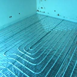 System ogrzewania podłogowego z rur rozprowadzonych na siatce w pomieszczeniu w trakcie remontu, widoczne otwory montażowe w ścianach.