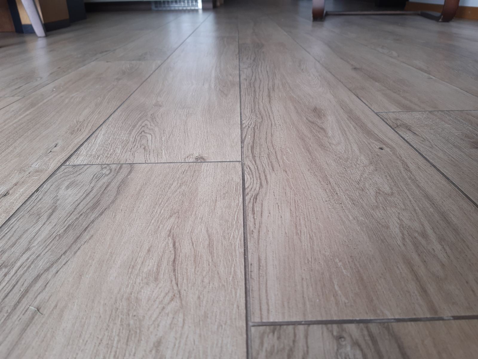 Ułożona podłoga z paneli imitujących drewno, widok z niskiej perspektywy, ukazujący strukturę i łączenia.