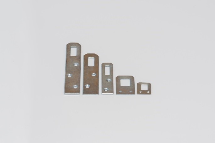 Różne rozmiary metalowych płytek mocujących ze stali, każda z kwadratowym otworem i otworami na śruby, ułożone w rzędzie na białym tle.