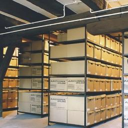 Archiwa Opolskie Sp. z o.o. - Regały magazynowe wypełnione kartonami z napisem 'Archiwa Opolskie' w pomieszczeniu z drewnianymi belkami stropowymi i instalacją elektryczną pod sufitem, dodatkowo widoczna gaśnica.