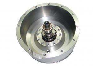 Metalowy element obrabiany maszynowo, widoczne ślady frezowania i wiercenia, wewnątrz łożysko i zębatka, całość na białym tle.