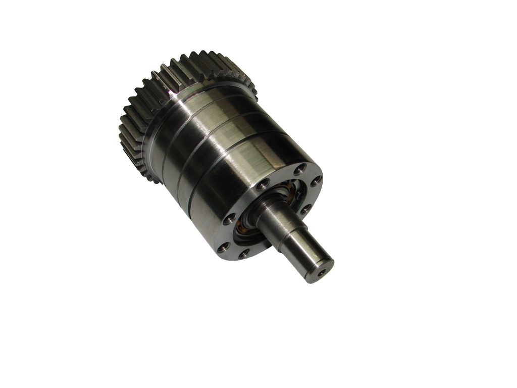 Metalowa przekładnia z zębatką i wałem, widoczne łożysko kulkowe, obrobiona na tokarce CNC, na białym tle.