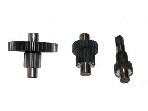 Trzy metalowe przekładnie zębate o różnych rozmiarach i konfiguracjach, ułożone na białym tle. Jedna przekładnia leży poziomo, dwie stoją pionowo. Widoczne ślady obróbki.