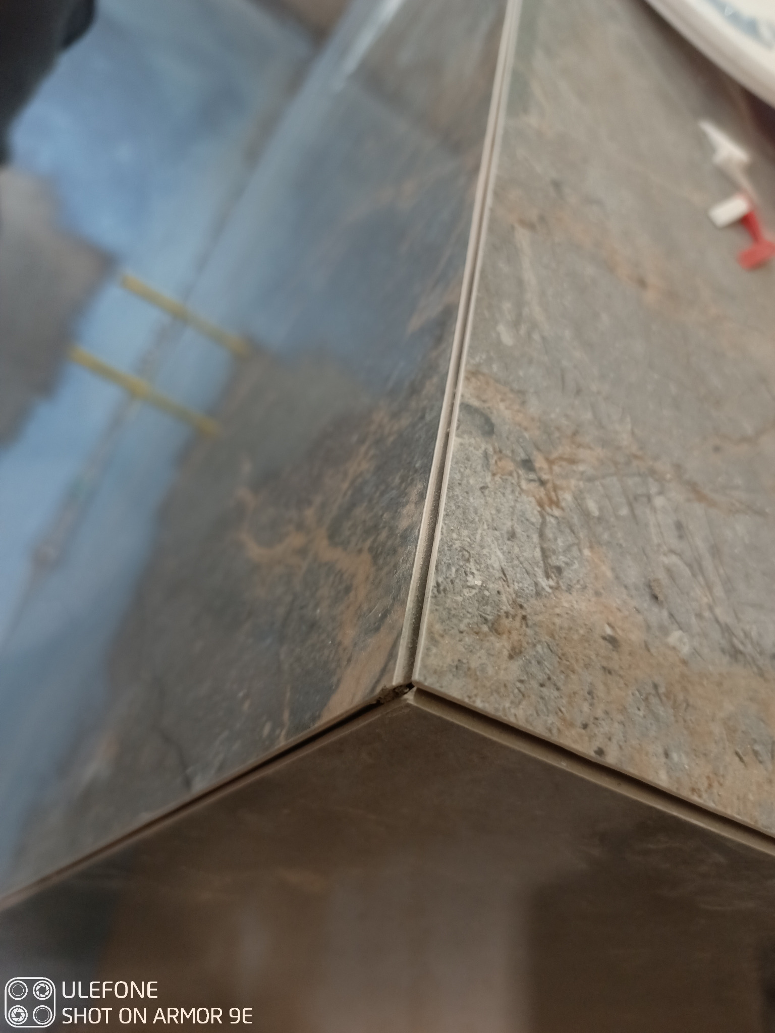 Szczegółowe ujęcie narożnika wykończonego płytkami imitującymi kamień, widoczne krzyżyki dystansowe, precyzyjne łączenie krawędzi.