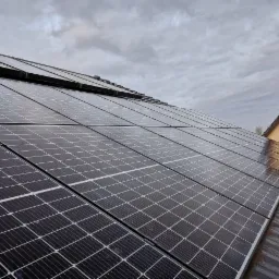 Panel słoneczny na dachu domu jednorodzinnego, widok pod kątem, pochmurne niebo w tle.