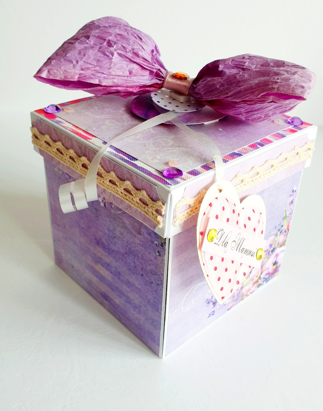 Ręcznie robione, fioletowe pudełko prezentowe z papieru z kokardą, koronką i zawieszką w kształcie serca z napisem 'Dla Mamusi'.