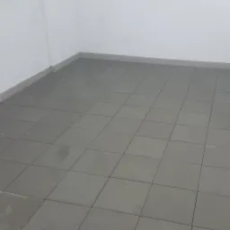 Wyłożony szarymi płytkami balkon z białymi ścianami, widok z góry, lekko pochmurne oświetlenie.