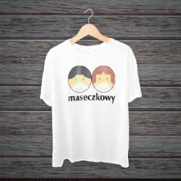 Biała koszulka z nadrukiem dwóch stylizowanych postaci w maseczkach i napisem 'maseczkowy', wisząca na wieszaku na tle drewnianej ściany.